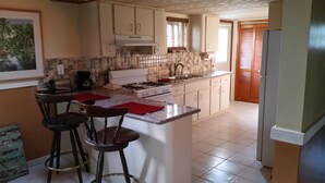 A kitchen with a central island, two bar stools, a coffee maker, and a stove. - 2 Bedroom 2bath cottage (Freeport)