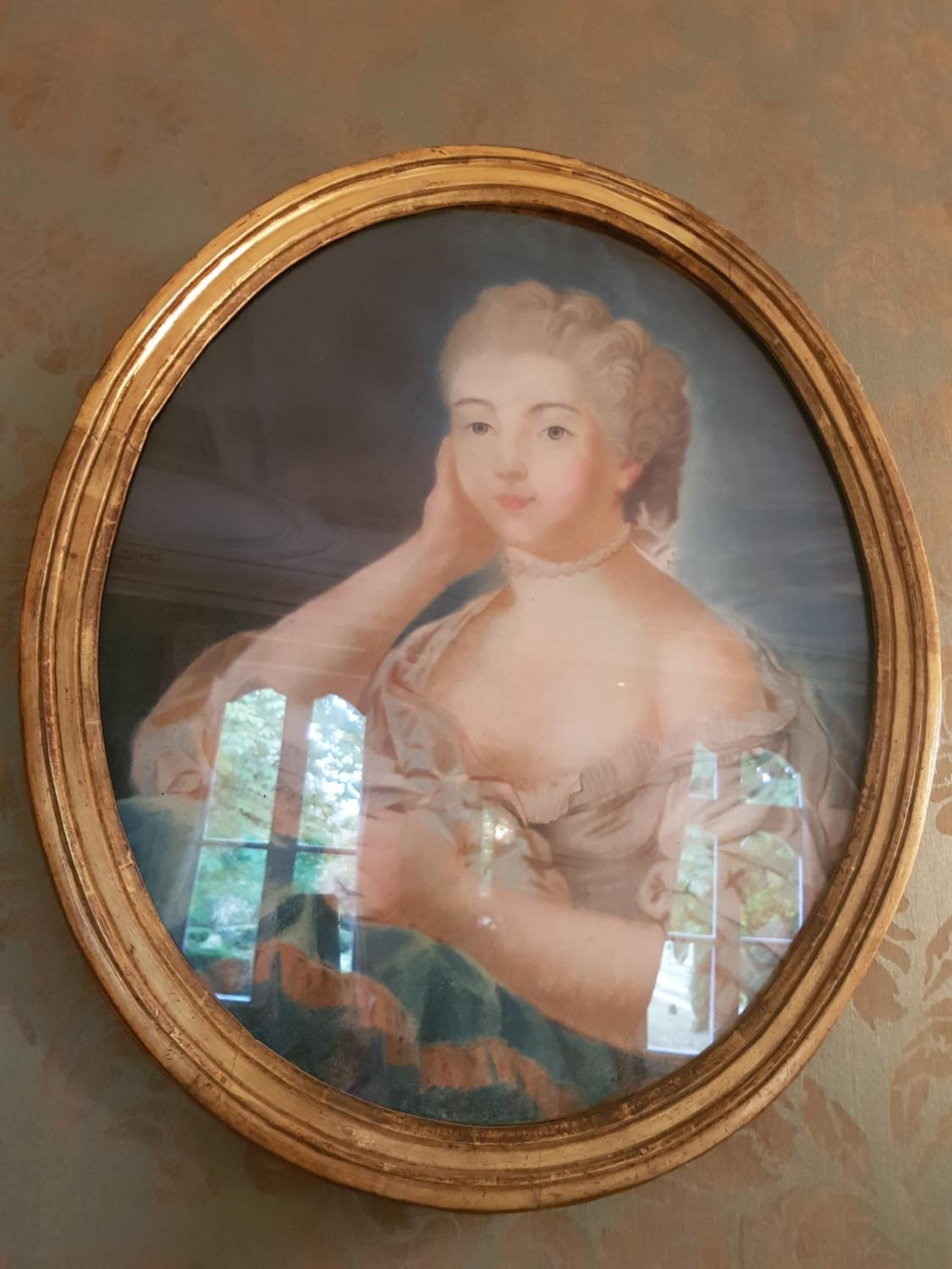 Ein gerahmtes Porträt mit goldener Rahmung, das an einer Wand mit strukturiertem Tapetenmuster hängt.