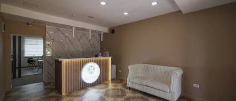 A reception area with a modern counter, a white sofa, and patterned flooring.