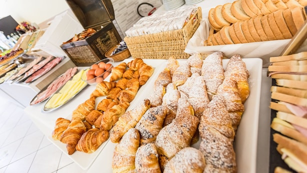 A variety of pastries and bread on display, including croissants, muffins, and bread rolls. - Gadames Hotel - Lunch on the Beach (Cervia)