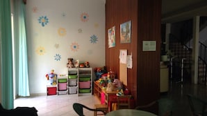 A room with a play area, a dining table, and chairs. There are colorful storage bins and toys on shelves. - Gadames Hotel - Lunch on the Beach (Cervia)
