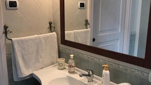 A bathroom with a white sink, a mirror, a towel rack, and a bottle of hand soap. - Maison de Charme Iommella (Sant'Agnello)
