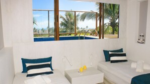 A hotel room with two beds, a small white nightstand, a window with a view of palm trees and a pool, and a wall-mounted light fixture. - Cobertura com Piscina Privativa | Pé na Areia | Vista Mar | Barra Bali | Destino BSM 417 (Barra de São Miguel)