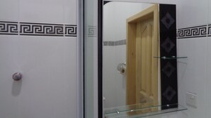 A bathroom with a mirror, a glass shelf, and a door with a wooden frame. - Queensland Hotel (Sekondi-Takoradi)