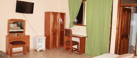 Un dormitorio con cama, un escritorio de madera, una silla, un televisor y un armario.