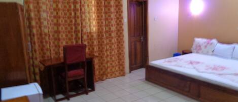 A bedroom with a bed, a desk, and a chair.