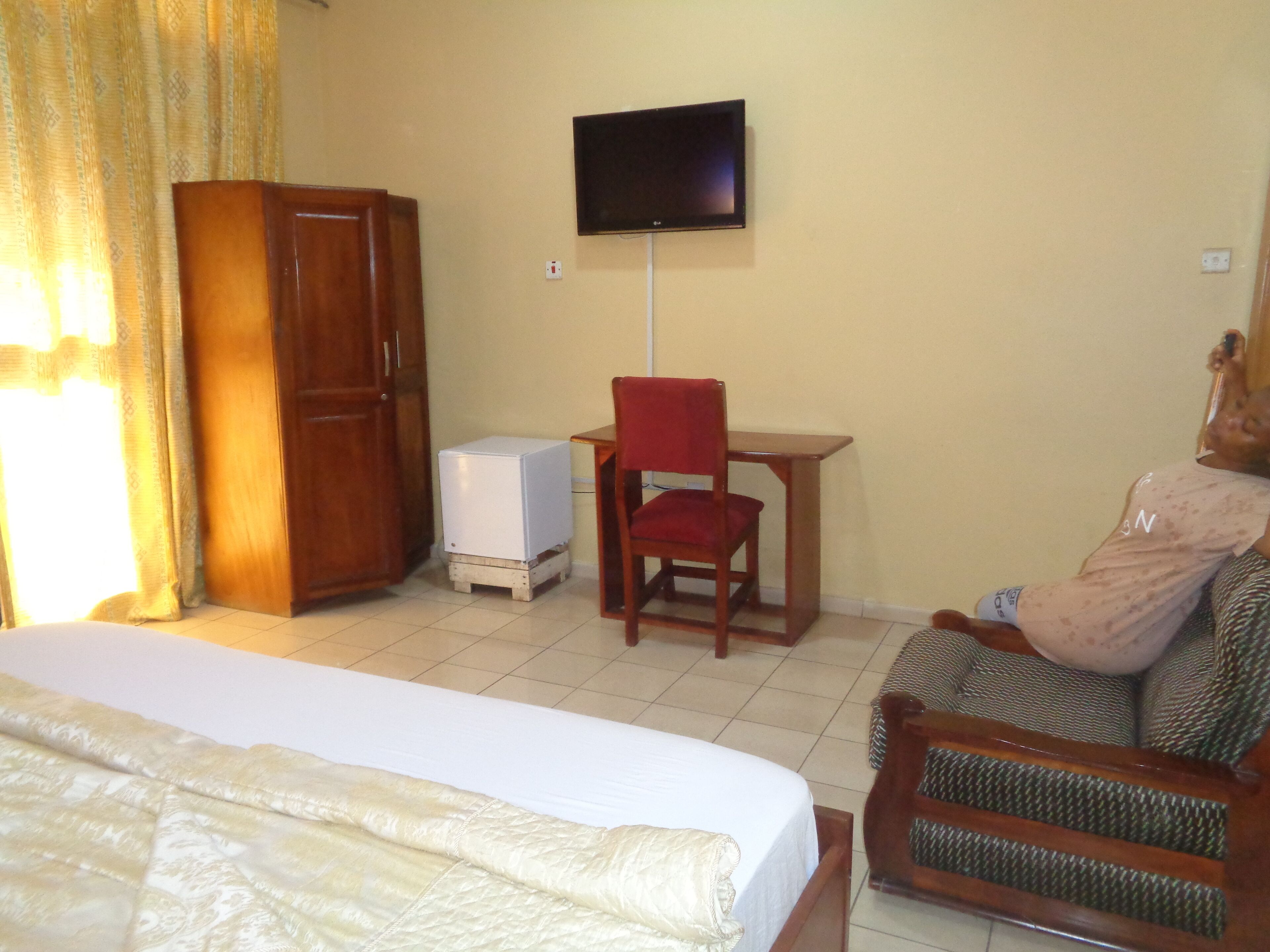 Una habitación de hotel con cama, escritorio, televisor y armario.