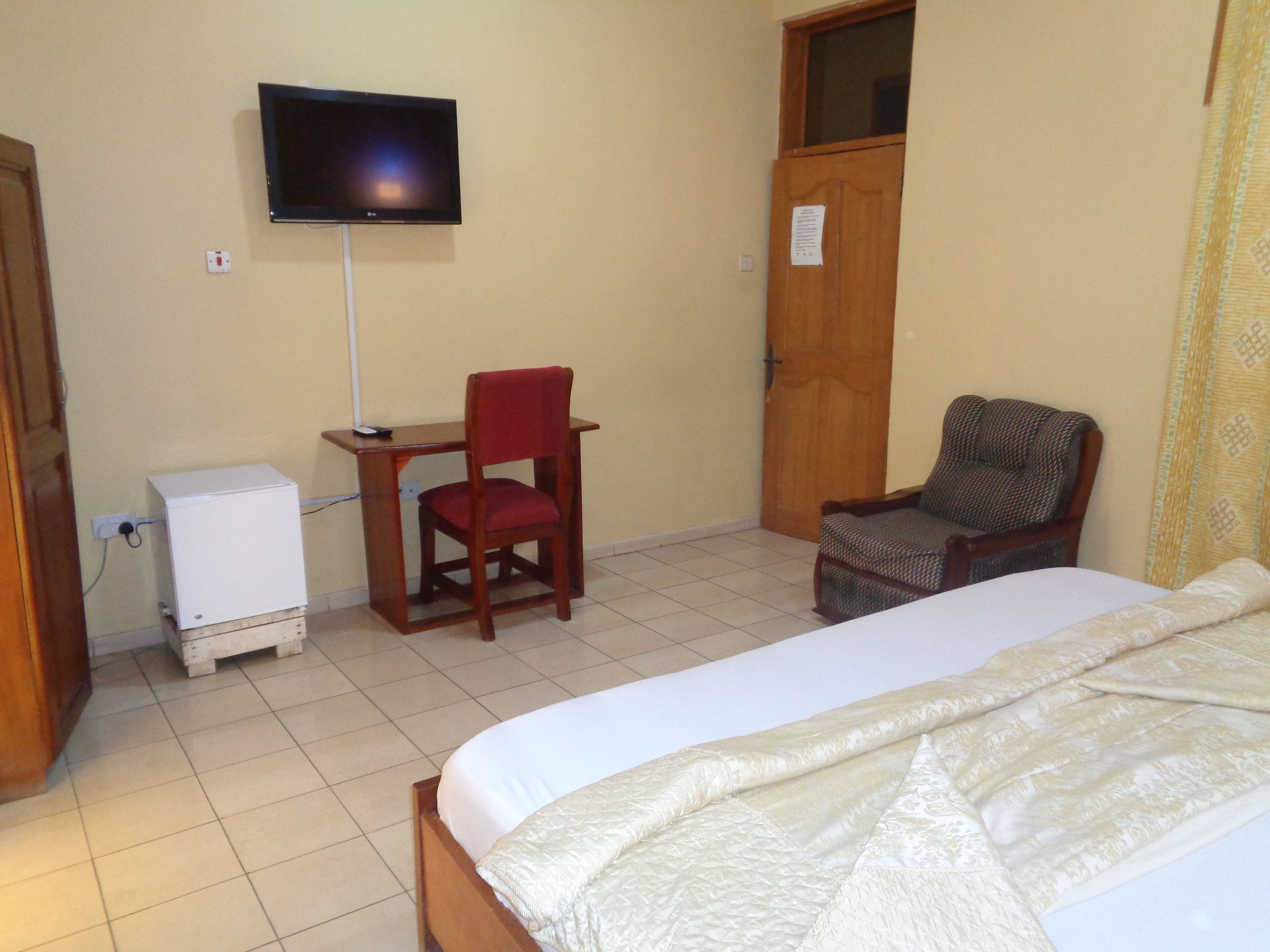 A bedroom with a bed, a desk with a chair, a television, and a wardrobe.