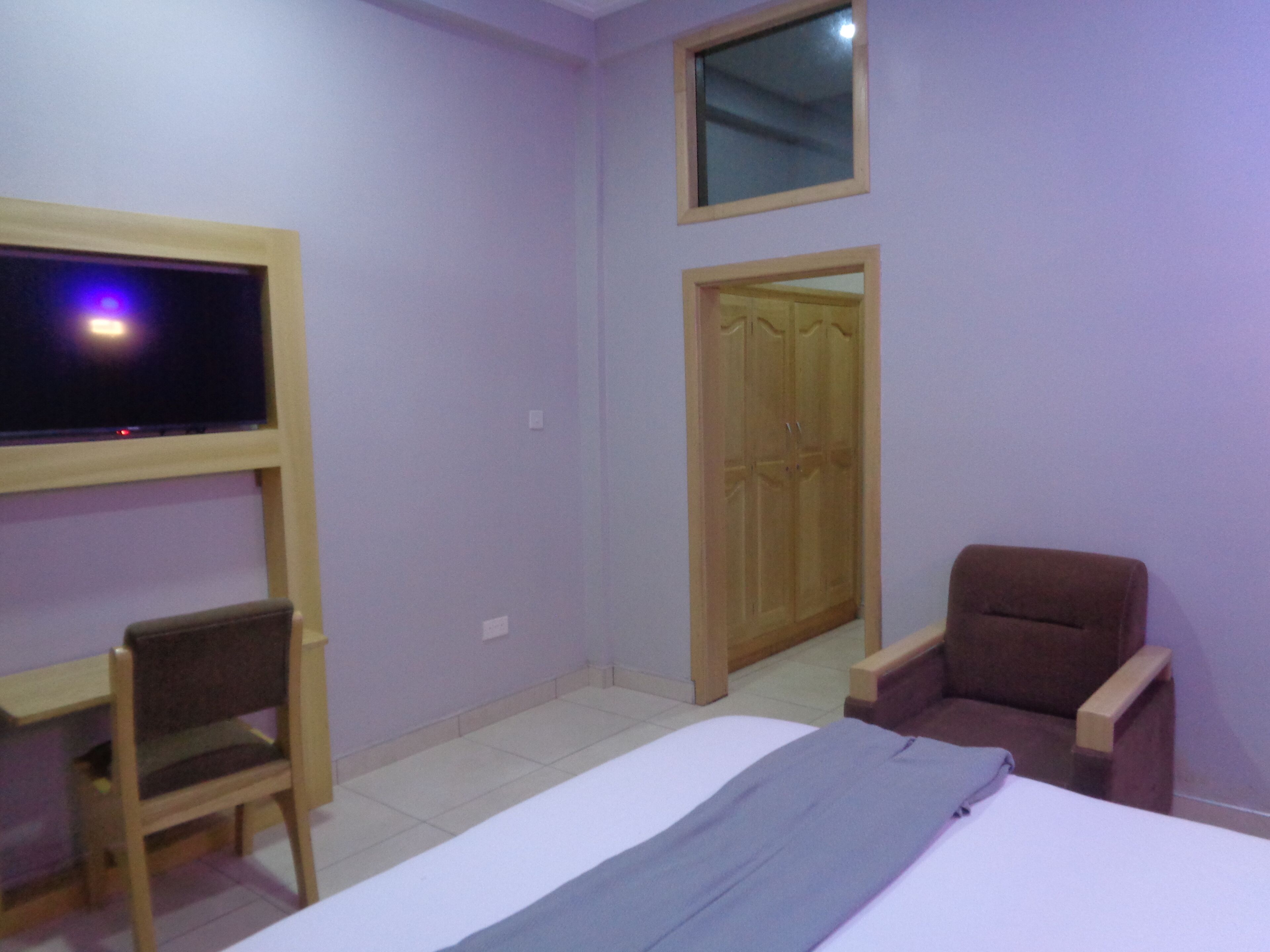 Un dormitorio con cama, escritorio, silla, armario y televisor.