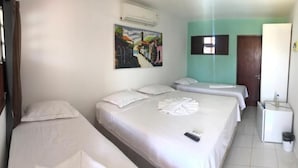 A hotel room with two beds, a small desk, a refrigerator, and a painting on the wall. - Pousada Carcará (Ipojuca)