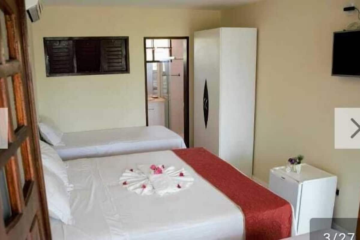 Habitación de hotel con dos camas, un armario, un televisor y una mesita.