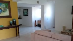 A spacious living room with a beige sofa, a wooden coffee table, and a painting on the wall. - Pousada Carcará (Ipojuca)