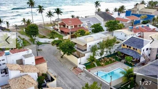 A coastal residential area with houses, a swimming pool, and palm trees. - Pousada Carcará (Ipojuca)