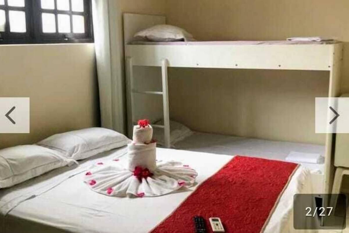 Habitación con literas, una cama bien hecha y una manta roja.