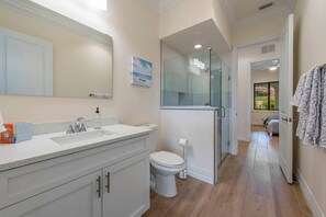 Bathroom features a large mirror, sink, toilet, and glass shower enclosure.