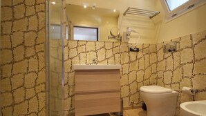 Une salle de bain avec un mur recouvert de carreaux à motifs, une douche en verre, un lavabo blanc et des toilettes.