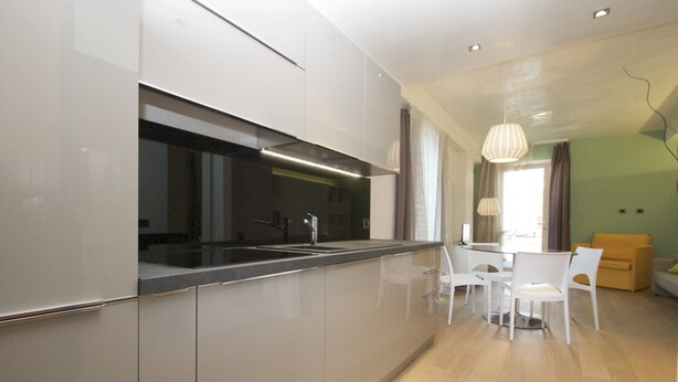 Une cuisine moderne dotée d’un îlot central, de meubles blancs et d’un coin repas avec une table et des chaises.