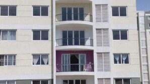 Un edificio residencial de varios pisos con balcones, ventanas grandes y fachada plana.
