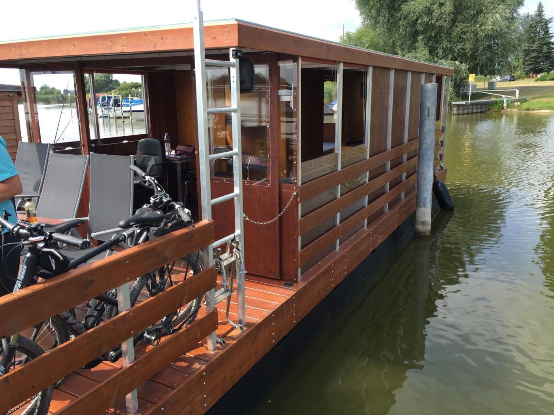 A wooden boat with a covered deck, bicycles, and a small table.