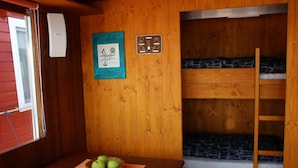A bunk bed room with a wooden wall, a table with a basket of apples, and a window with blinds. - Hausboot Radewege am Beetzsee (Beetzsee)