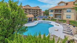A swimming pool surrounded by lounge chairs and a stone patio, with a multi-story building in the background. - Branson Lakefront Penthouse at The View- Emerald Pointe! (Hollister)