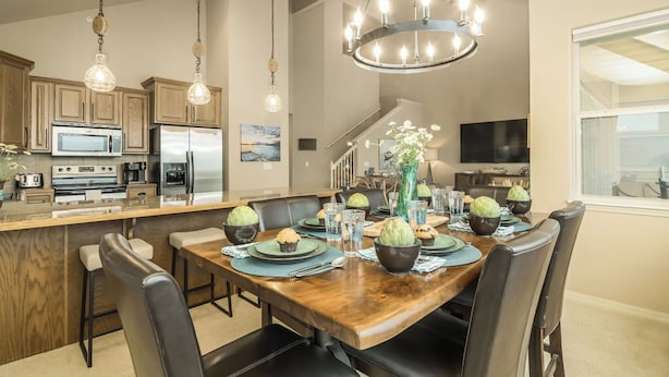 A modern kitchen with built-in appliances, a dining area with a wooden table and chairs, and a chandelier. - Branson Lakefront Penthouse at The View- Emerald Pointe! (Hollister)