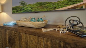A wooden console table with a decorative bowl containing glassware, a framed photograph, and a small sculpture. - Branson Lakefront Penthouse at The View- Emerald Pointe! (Hollister)