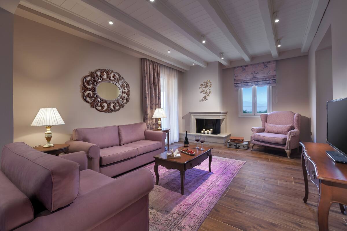 A living room with a sofa, armchairs, a coffee table, a fireplace, and a television.