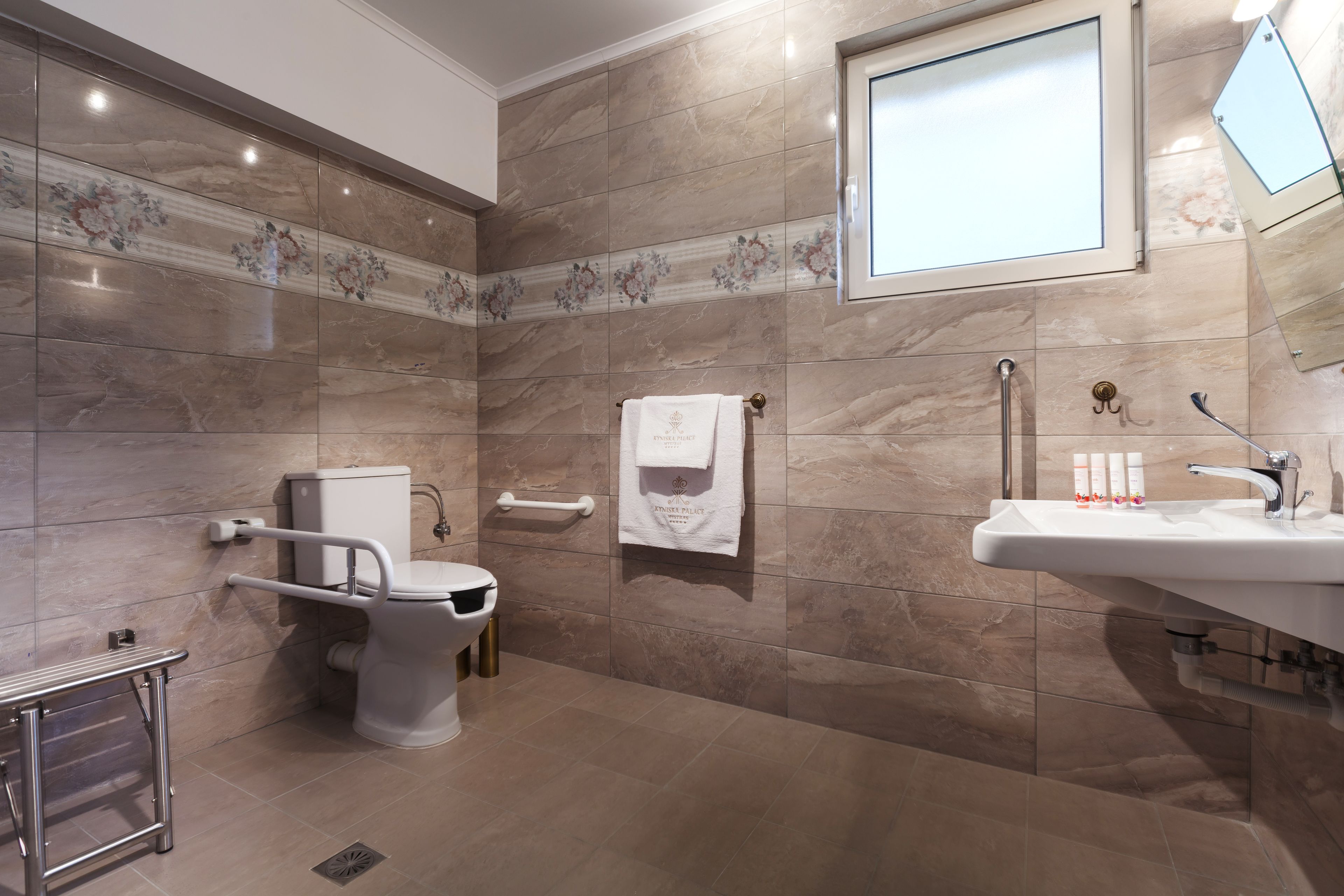 Et moderne badeværelse med toilet, gelænder, vask og spejl.