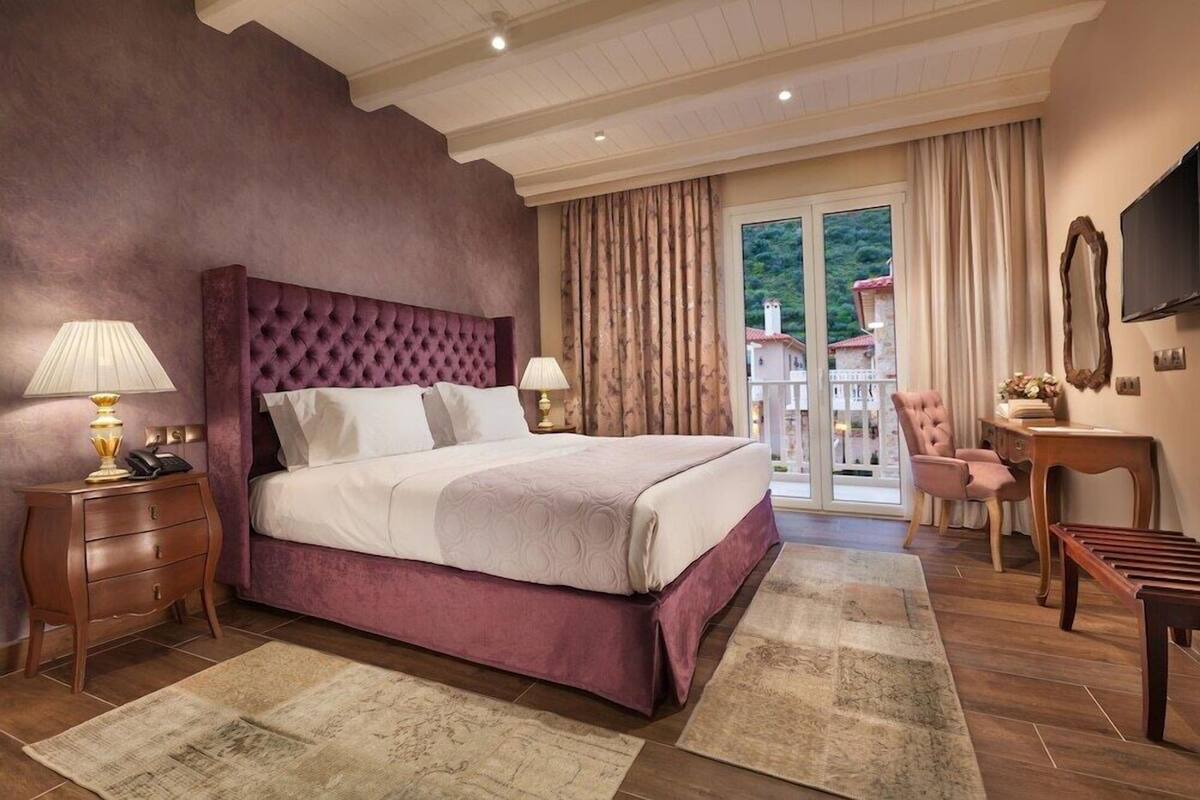 A bedroom with a large bed, two bedside tables, a chair, a desk, and a TV.