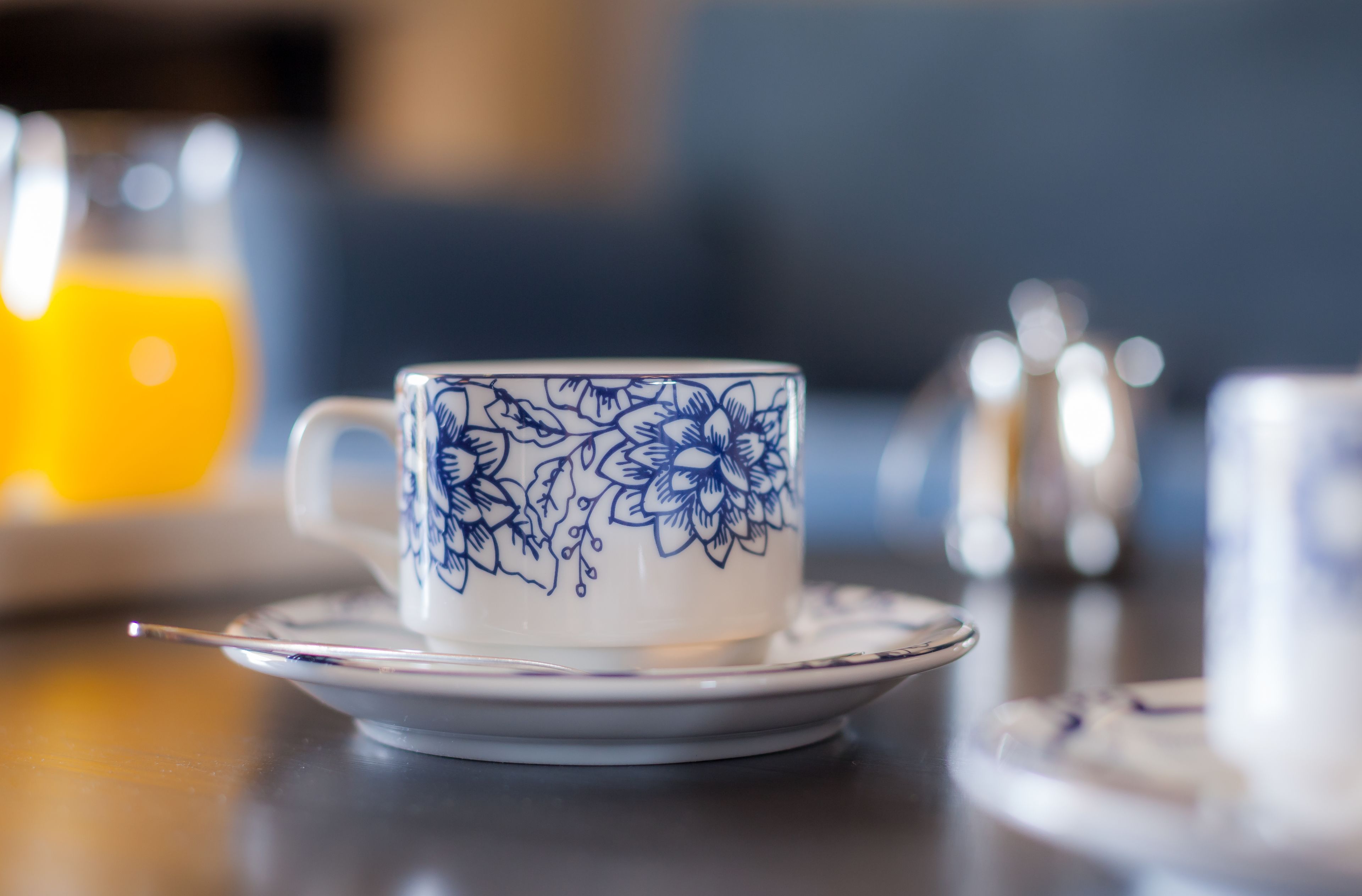 Een kop met een bloemenmotief op een schoteltje, geplaatst op een tafel.