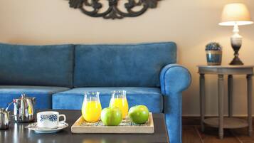 A living room with a blue sofa, a coffee table with a tray holding a cup, a teapot, and two apples.