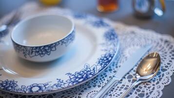 A table setting with a bowl and cutlery on a lace tablecloth.