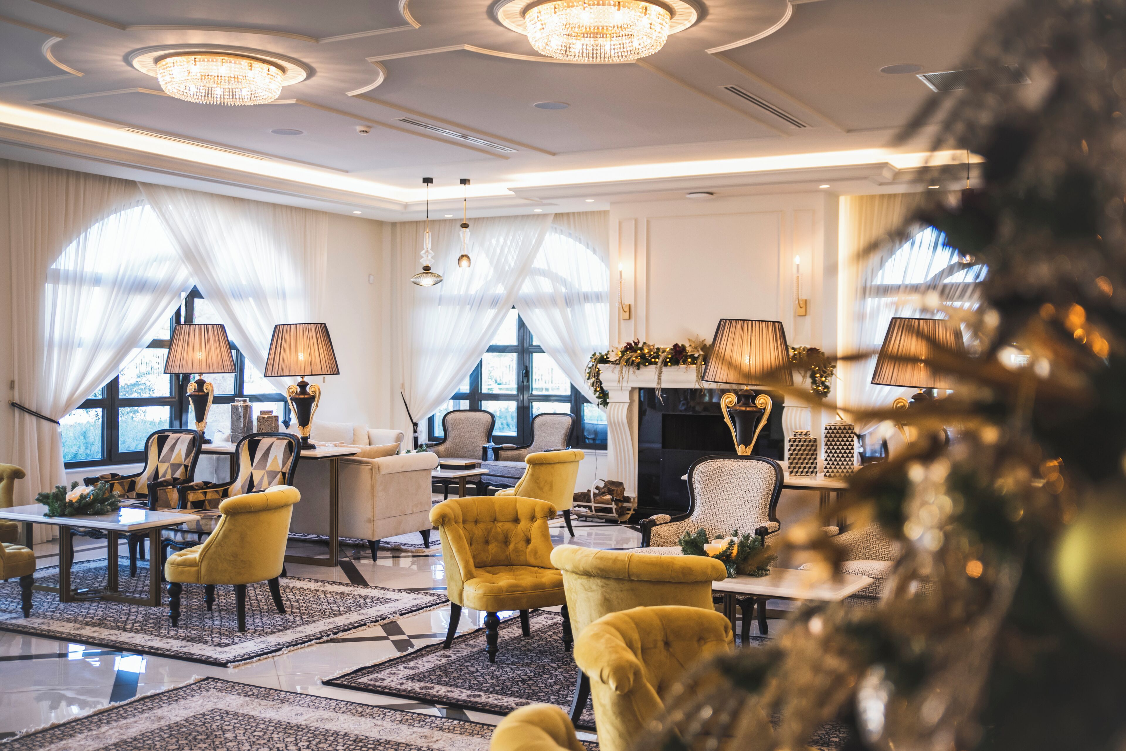 A spacious lounge area with a fireplace, comfortable seating, and large windows allowing natural light.