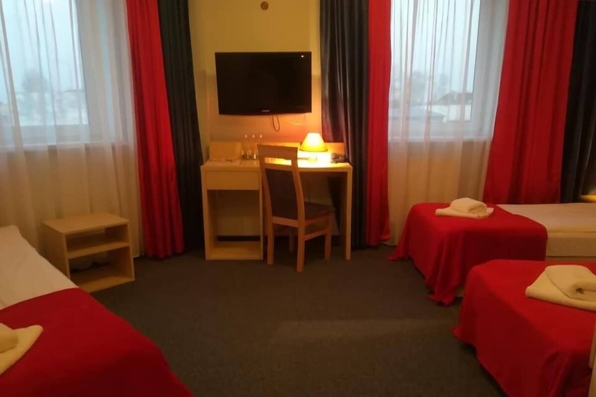 A hotel room with two beds, a desk with a chair, a television, and a lamp.