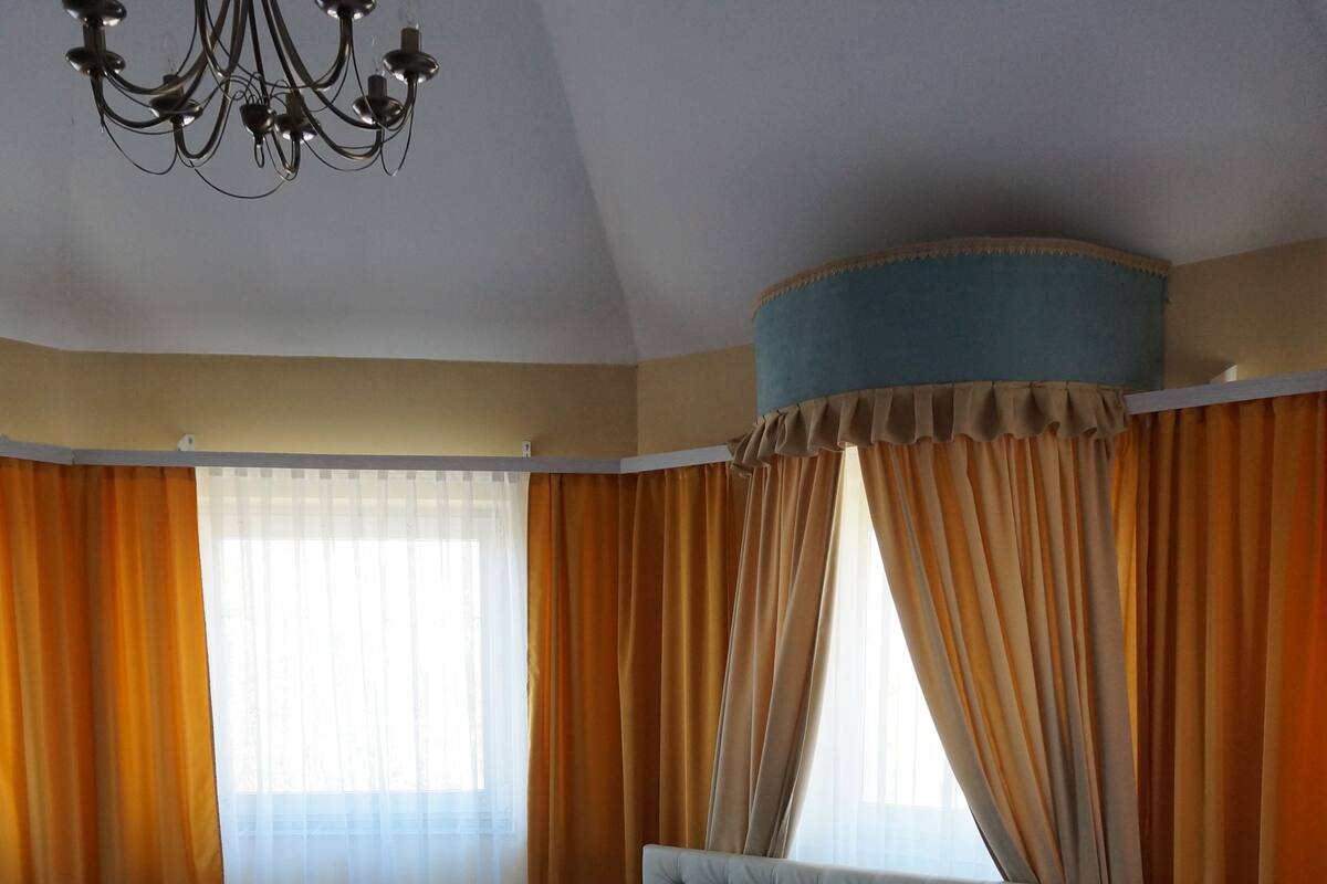 A bedroom with a large bed, a chandelier, and curtains.