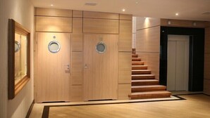 Un interior moderno con paneles de madera, una escalera y una puerta con un ventanal circular.