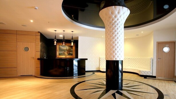 Un vestíbulo con mostrador de recepción, una columna decorativa grande y un suelo estampado.