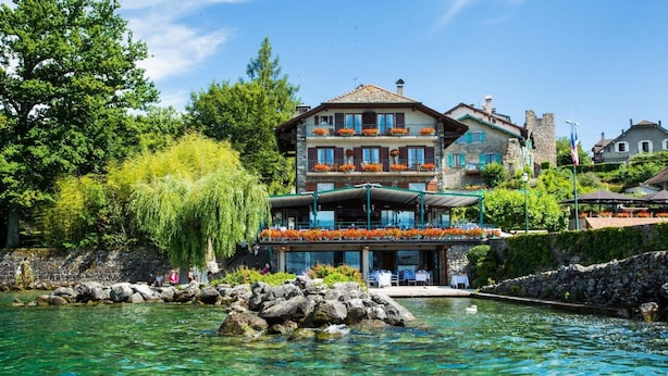 Un edificio de varios pisos con terraza al aire libre y vista despejada de un lago.
