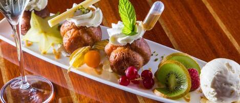 Een dessertbord met diverse soorten fruit en een glas champagne op een houten tafel.