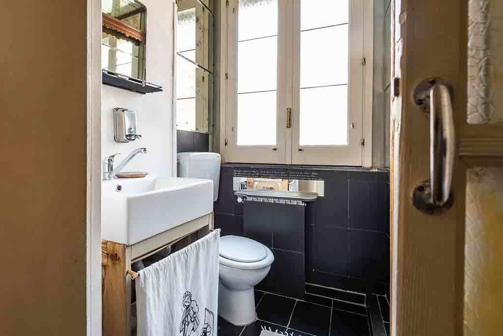 A compact bathroom with a white sink, a toilet, and a window.
