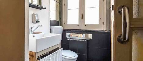 A compact bathroom with a white sink, a toilet, and a window.