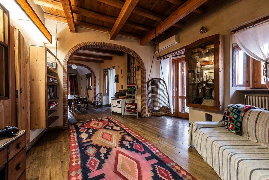 Ein gemütliches Zimmer mit Holzbalken, einem gemusterten Teppich und einem Sofa mit einer Quilttdecke.