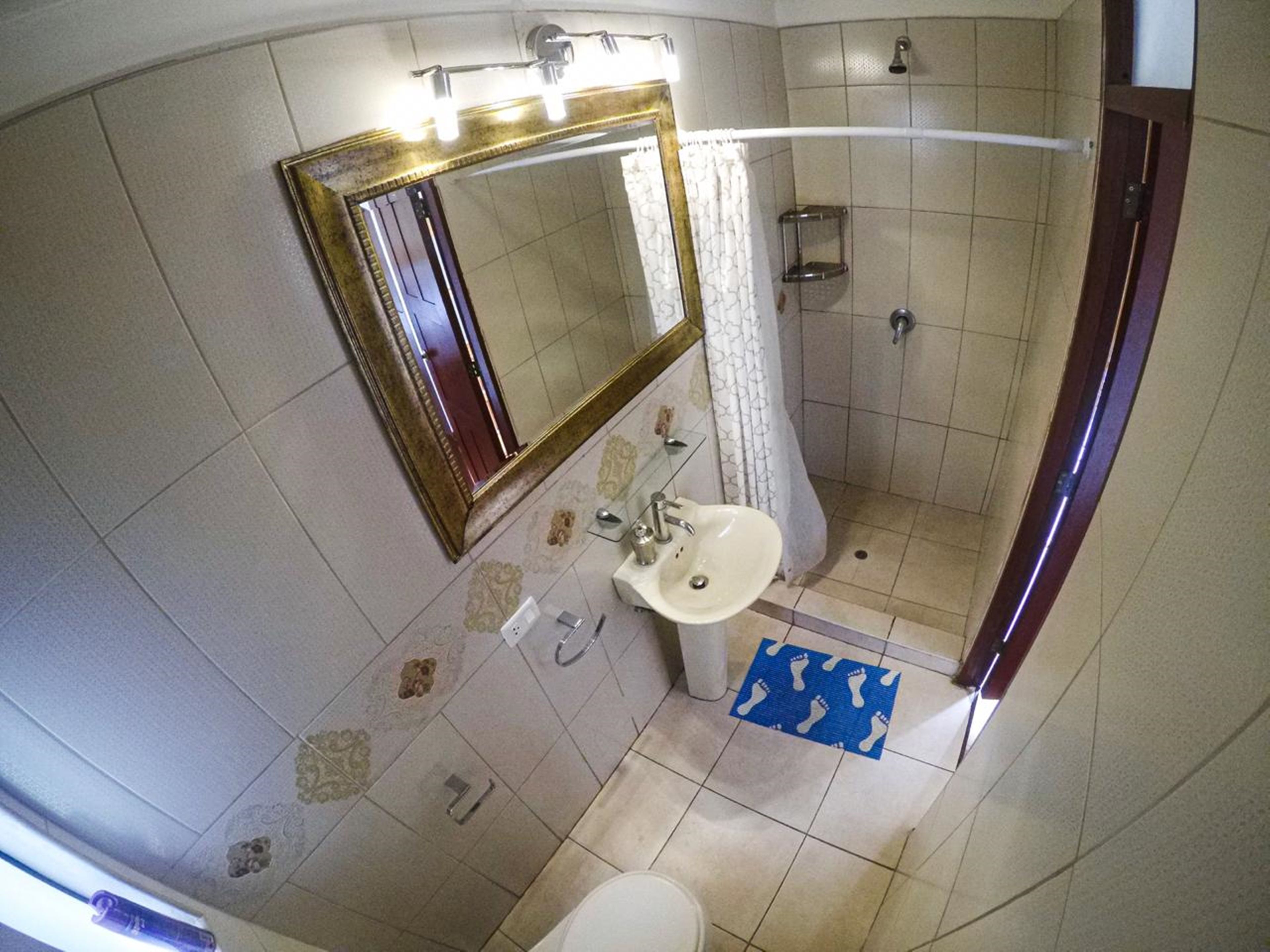 A bathroom with a sink, mirror, and shower.