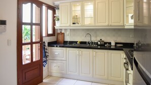 A kitchen with white cabinets, a black countertop, and a wooden door. - Lima White House - Hostel (Lima)