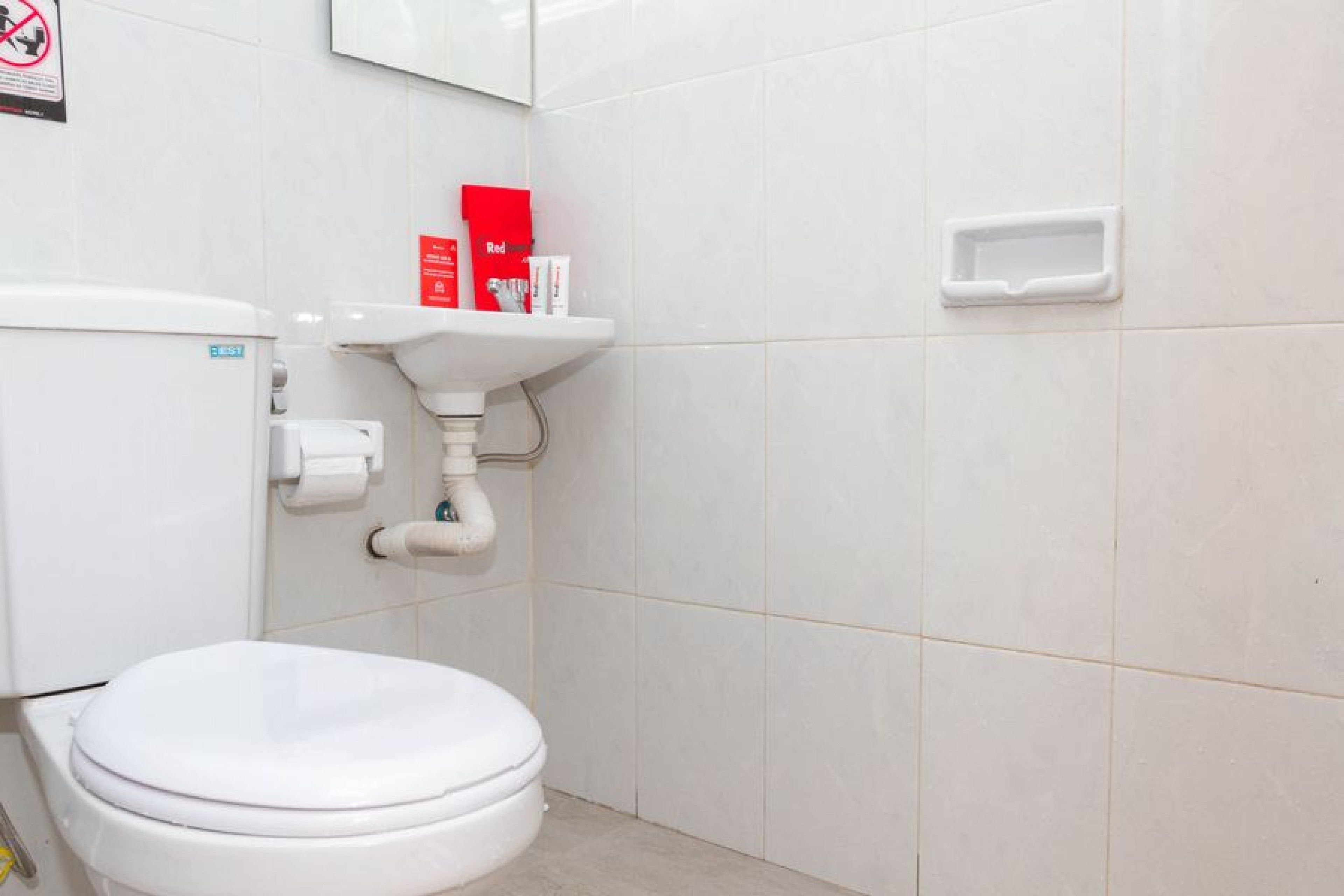 A small, clean bathroom with a toilet, sink, and a red box on the wall.