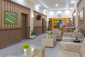 A hotel lobby with a reception desk, seating area, and a clock on the wall. - RedDoorz near Istana Plaza 2 (Bandung)