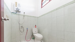Een kleine badkamer met toilet, douche en een wandradiator.