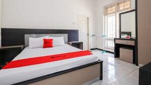 Una habitación de hotel con cama, escritorio, espejo y ventana.