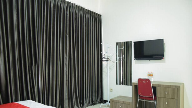 A hotel room with a bed, a desk, a chair, a television, and a wardrobe. - RedDoorz near GOR Satria Purwokerto (Purwokerto)